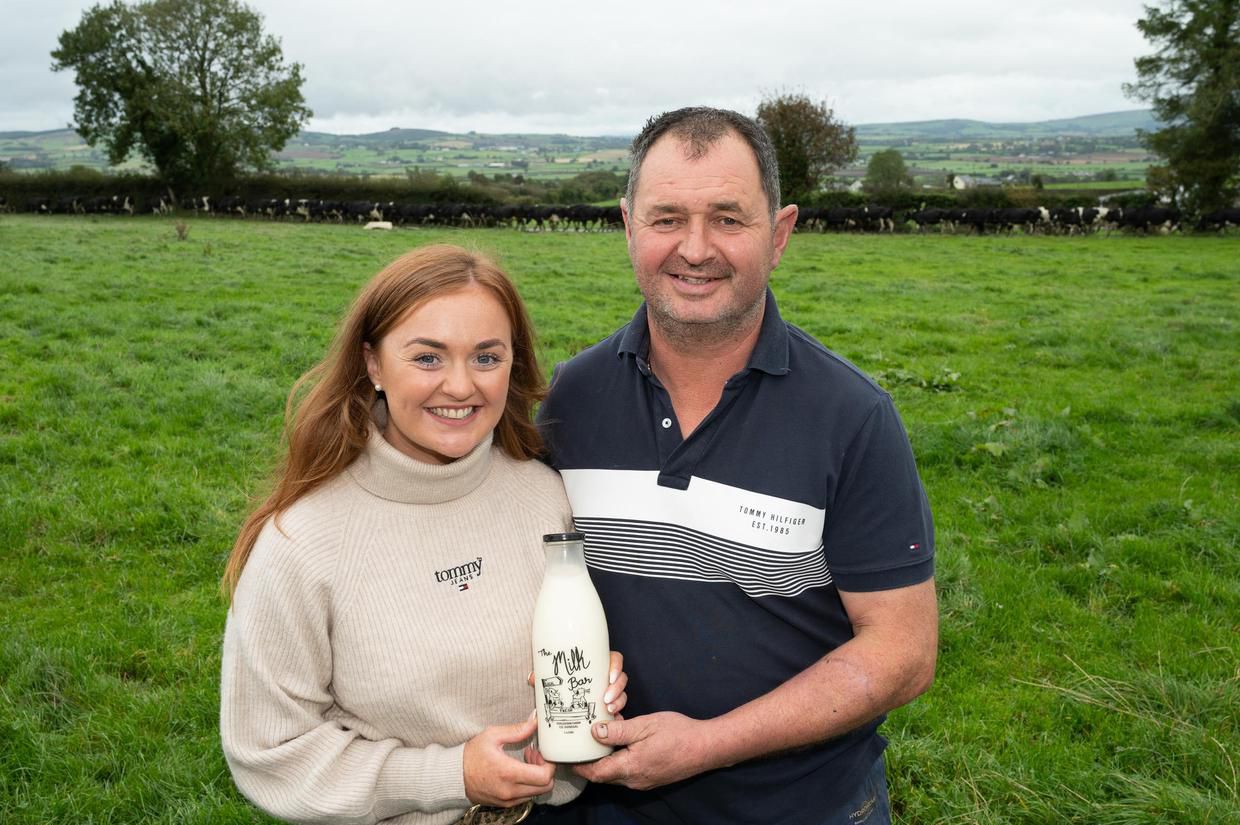The family standing in the field with a bottle of The Milk Bar milk, herd in the background