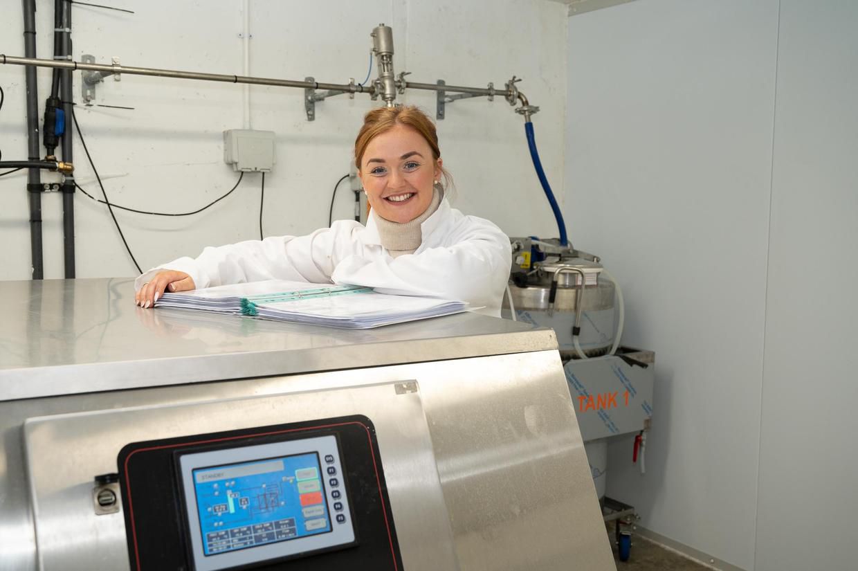Megan in the on-farm pasteurisation room beside the tank
